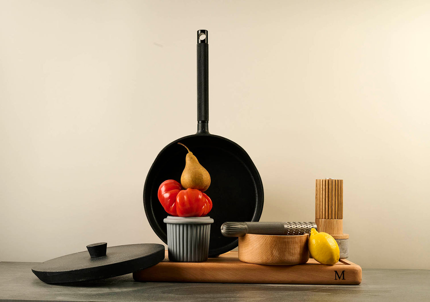 Black cast iron pan with fruits on a wooden cutting board against a plain background.
