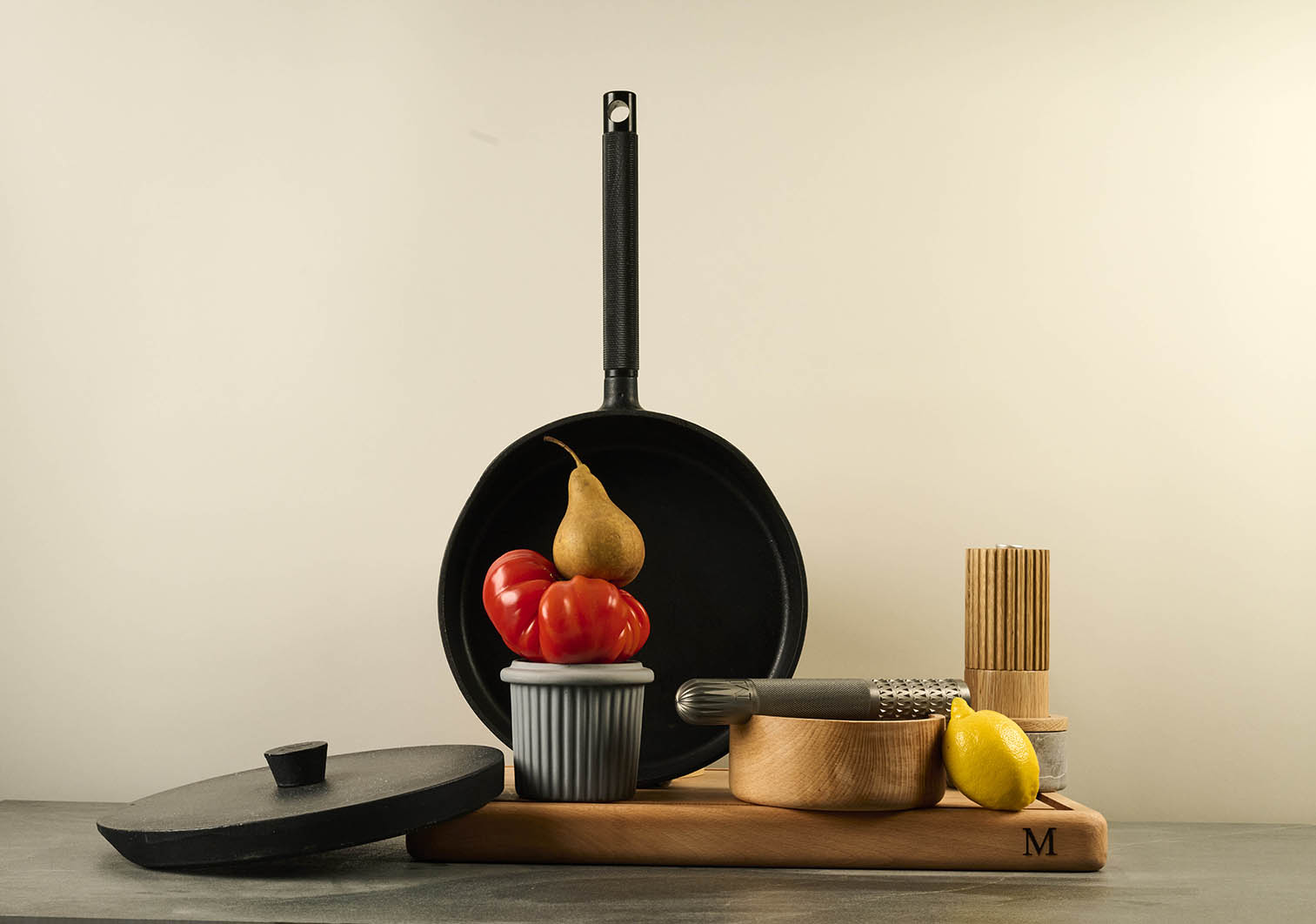 Black cast iron pan with fruits on a wooden cutting board against a plain background.