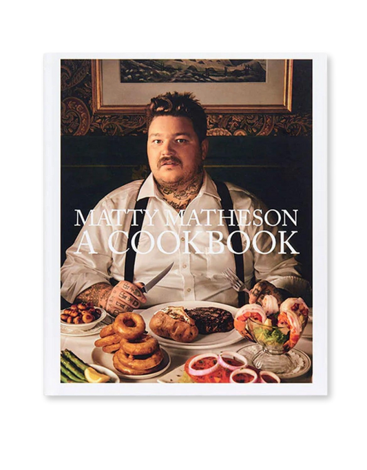 The cover of 'Matty Matheson: A Cookbook' features a photograph of Matty Matheson sitting at a table filled with various dishes, including poutine, a popular Canadian snack.